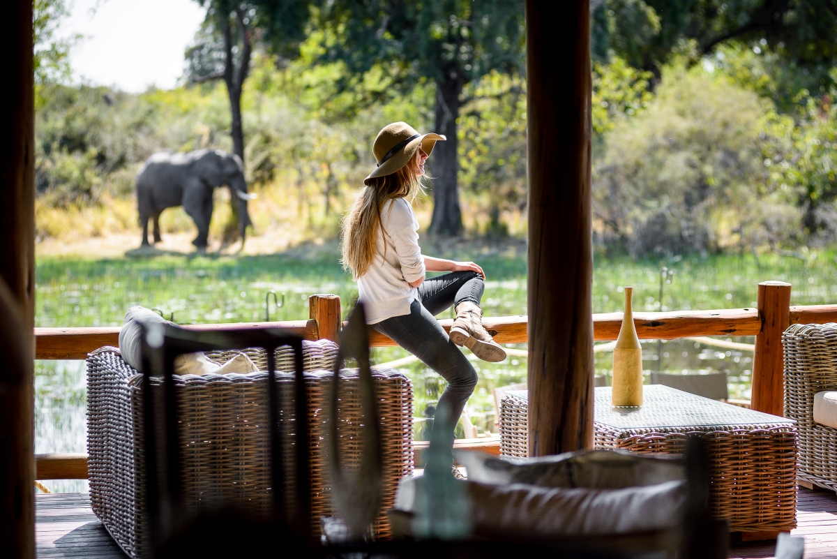 Sanctuary-Chief's-Camp-viewing-deck-with-elephant Woman on the viewing deck with an elephant in the distance