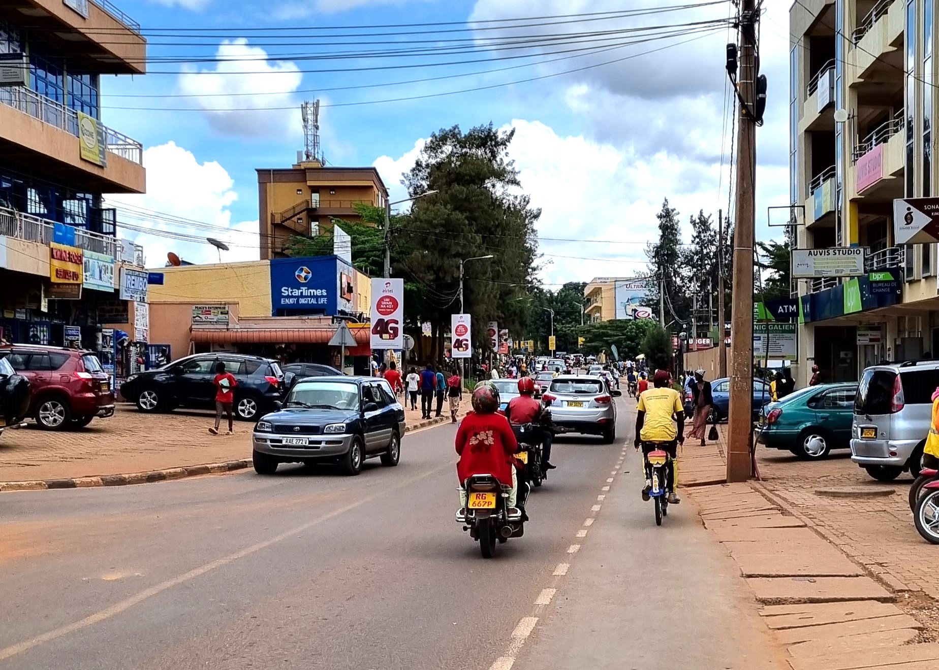 Allison-trip-to-Kigali-rwanda City street with vehicles, scooters and a cyclist, no litter in sight