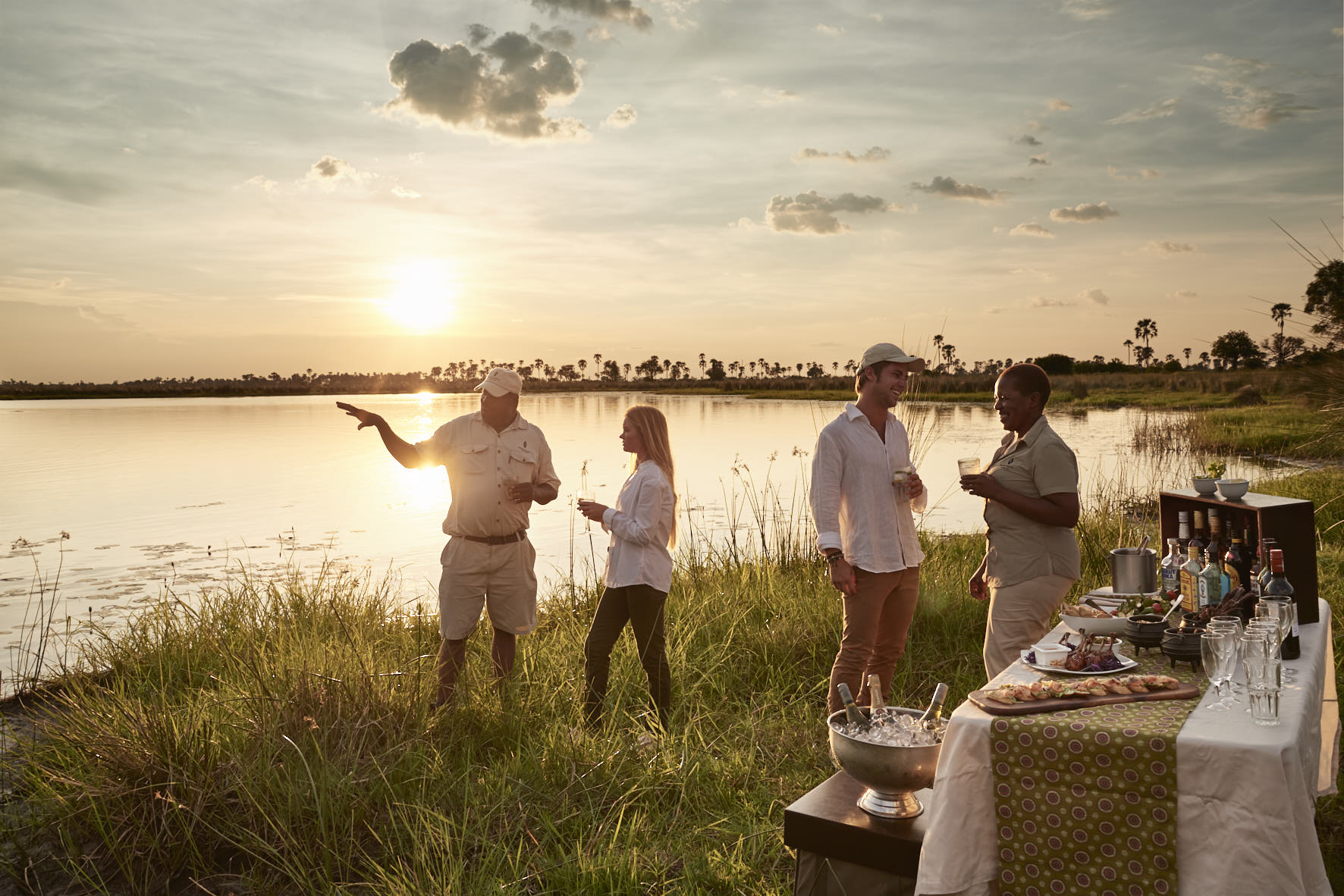 baines_camp_subdowner Guests sharing sundowners and conversation with local staff in Botswana